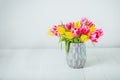 Fresh spring yellow and pink tulips bouquet in blue vase on white wooden table with white background. Festive flowers for mother` Royalty Free Stock Photo