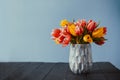 Fresh spring yellow and pink tulips bouquet in vase standing on black wooden table with gray blue background. Festive Royalty Free Stock Photo