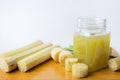 Fresh squeezed sugar cane juice in clear glass with cut pieces cane on white background Royalty Free Stock Photo