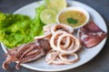 Fresh squid cooked boiled with lettuce vegetable salad lemon and seafood sauce on table background, squid rings on white plate Royalty Free Stock Photo