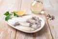 Fresh squid tubes on a plate over wooden table. Small calamary fillet, lemon and olive oil prepared for cooking. Raw squid for low Royalty Free Stock Photo