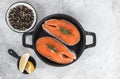 Fresh steaks of red salmon fish with spices, herbs and lemon in a black pan Royalty Free Stock Photo