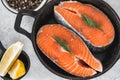 Fresh steaks of red salmon fish with spices, herbs and lemon in a black pan Royalty Free Stock Photo