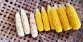 Fresh steamed corn with stainless steel tongs on bamboo weave tray for sale at street food market