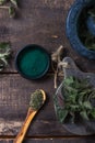 Fresh stinging nettle leaves on wooden table.Urtica dioica oil with spirulina powder, a healthy supplement to improve health