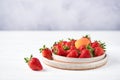 Fresh strawberries and apricot in two ceramic plates on a white wooden table and a gray background