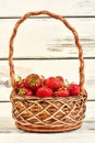 Fresh strawberries in basket on white wooden background. Royalty Free Stock Photo