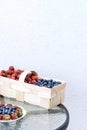 Fresh strawberries and blueberries lie in a plate and basket on a glass table against the background of a plastered white wall. Royalty Free Stock Photo