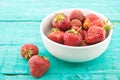 Fresh strawberries in a ceramic bowl on turquoise rustic wooden