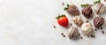 Fresh strawberries covered in dark and white chocolate on a textured light surface with scattered chocolate chips Royalty Free Stock Photo
