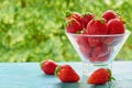 Fresh strawberries in a glass bowl on the blue kitchen table on the blurred nature background. Tasty vegan summer dessert Royalty Free Stock Photo