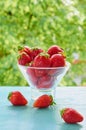 Fresh strawberries in a glass dessert bowl on the blue kitchen table on the blurred nature background. Vegan summer breakfast Royalty Free Stock Photo