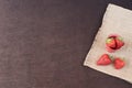 Fresh strawberries in mini metal bucket on hessian jute. Black background.