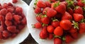Fresh strawberries and raspberries on white plates