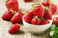 Fresh strawberries in a white porcelain bowl on wooden table in Royalty Free Stock Photo