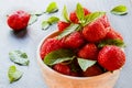 Fresh strawberries in white vintage bowl on black stone. Green mint leaves and ripe berries from garden on background Royalty Free Stock Photo