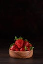 Fresh strawberries in a wooden bowl on a brown background