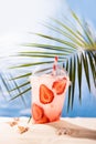 Fresh strawberry beverage with ice, straw in plastic glass on sandy tropical beach with sea view, copy space, vertical. Vacation. Royalty Free Stock Photo