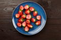 Fresh strawberry in blue plate on dark wooden background Royalty Free Stock Photo