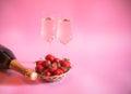 Fresh strawberry, bottle of champagne and glasses of champagne on pink background. Selective focus Royalty Free Stock Photo