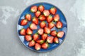 Fresh strawberry cut in half on blue ceramic plate on grey background Royalty Free Stock Photo