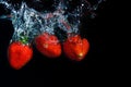 fresh strawberry dropped into water with splash on black backgrounds Royalty Free Stock Photo