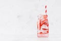 Fresh strawberry lemonade with sliced berry, soda water, ice cubes with straw in transparent jar on soft light white wood table. Royalty Free Stock Photo