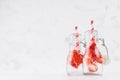 Fresh strawberry lemonades with sliced berry, soda water, straw in transparent yoke bottles on soft light white wood table.