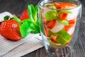 Fresh strawberry mojito or lemonade with mint and ice cubes on dark wooden table