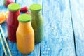 Fresh strawberry, orange and broccoli smoothie in bottles with fruits and vegetables on a blue wooden rustic background, close up Royalty Free Stock Photo