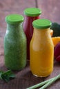 Fresh strawberry, orange and broccoli smoothie in bottles with fruits and vegetables on a brown wooden rustic background. vertical Royalty Free Stock Photo