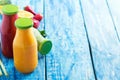 Fresh strawberry, orange and broccoli smoothie in bottles with fruits and vegetables on a blue wooden rustic background Royalty Free Stock Photo