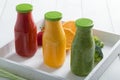 Fresh strawberry, orange and broccoli smoothie in three bottles with fruits and vegetables on a white wooden rustic background Royalty Free Stock Photo