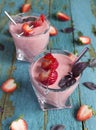 Fresh strawberry smoothies in a glasses with metal straws, basil leaves, strawberries on cocktail stick on old wooden surface. Royalty Free Stock Photo