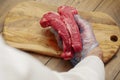 Fresh strip loin steak in a butcher hand over wooden cutting board. Premium product of meat industry. Juicy beef cut. Butcher