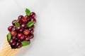 Fresh summer cherry berries with mint in waffle cone on white marble background. summer food concept. flat lay