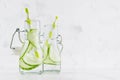 Fresh summer cocktails with green cucumber, soda, straw in yoke bottles on elegant soft light white wooden board and plaster wall. Royalty Free Stock Photo