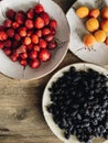 fresh summer fruits in ceramic bowls on wooden table in the kitchen. blueberries, apricots, strawberries, mulberry from market. Royalty Free Stock Photo