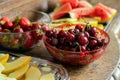 Fresh summer fruits: cherries, organic strawberries, melon slices, water melon in vintage crystal bowl on old wooden table Royalty Free Stock Photo