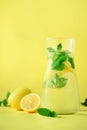 Fresh summer fruits water or lemonade with mint, ice, lemon on yellow background. Copy space. Summer infused water Royalty Free Stock Photo