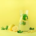 Fresh summer fruits water or lemonade with mint, ice, lemon on yellow background. Square crop. Copy space. Summer Royalty Free Stock Photo