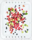 Fresh summer garden berries variety on white baking tray over light wooden backdrop Royalty Free Stock Photo