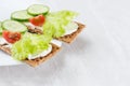 Fresh summer healthy appetizer of whole grain rye crisps breads with vegetables - green salad, cucumber, tomato, cream cheese. Royalty Free Stock Photo