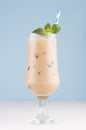 Fresh summer ice coffee in wet exquisite transparent glass with ice cubes, straw, green mint in light blue interior, vertical. Royalty Free Stock Photo