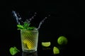 Fresh summer mojito cocktail with splashing isolated on dark background.Party rum refreshing drink with fresh limes and mint Royalty Free Stock Photo