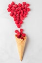 Fresh summer raspberries in waffle ice cream cone with heart made of berries on white marble background Royalty Free Stock Photo