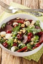 Fresh summer salad of arugula, baked beets, cherries, mozzarella, hazelnuts close-up in a bowl. Vertical Royalty Free Stock Photo