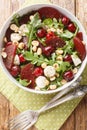 Fresh summer salad of arugula, baked beets, cherries, mozzarella, hazelnuts close-up in a bowl. Vertical top view Royalty Free Stock Photo
