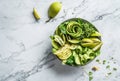 Fresh summer salad with avocado, kiwi, apple, cucumber, pear, micro greens, lime and sesame on light marble background. Healthy Royalty Free Stock Photo