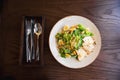 Fresh summer salad Ceasar with eggs, lettuce, chicken and parmesan cheese on white plate on wooden background; healthy concept Royalty Free Stock Photo